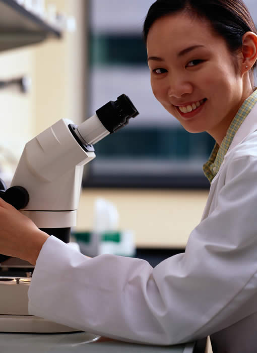 A freshman in the lab uses a microscope.