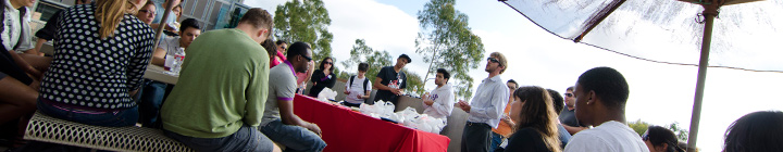 Students sitting down at a table listening to speaker