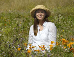 Elsa Cleland poses in a field of native Californian wildflowers, including a stand of golden poppies