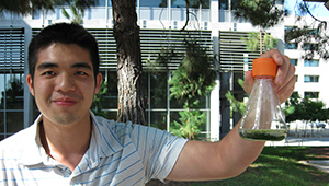 Francis Hwee holding a flask of cyanobacteria