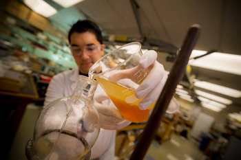 Researcher pouring a liquid into a beaker