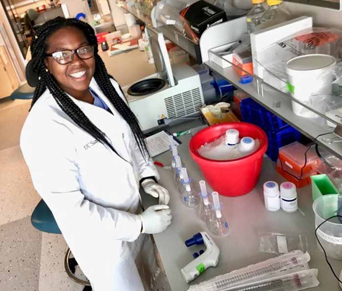 African-American student posing to have her photo taken while working at a lab bench