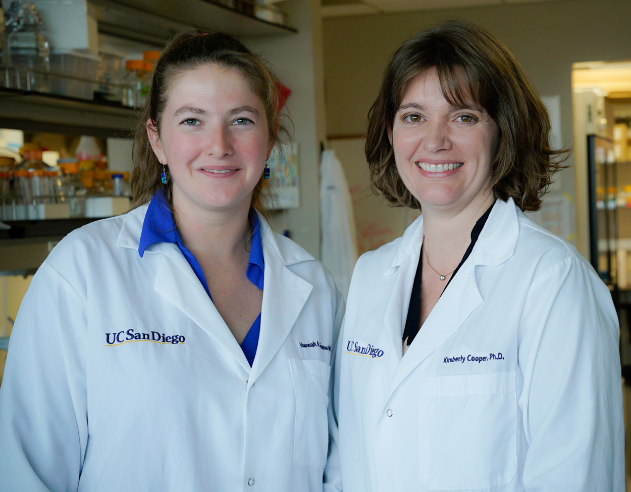 Hannah Grunwald and Assistant Professor Kimberly Cooper wearing lab coats inside Cooper's lab
