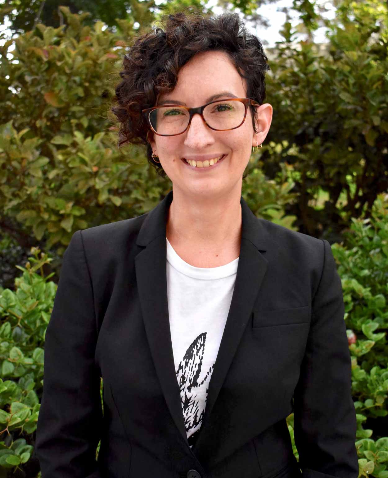 Short haired brunette woman with glasses smiling at camera